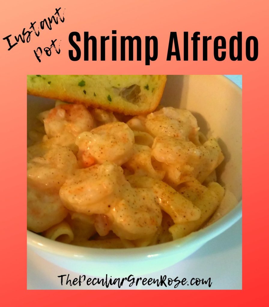 White bowl with cooked shrimp alfredo and a garlic bread.