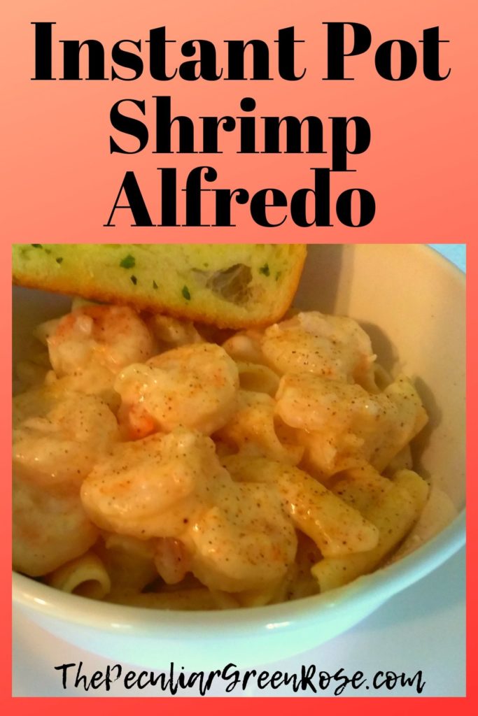 A white bowl filled with shrimp alfredo and penne noodles with a garlic bread.