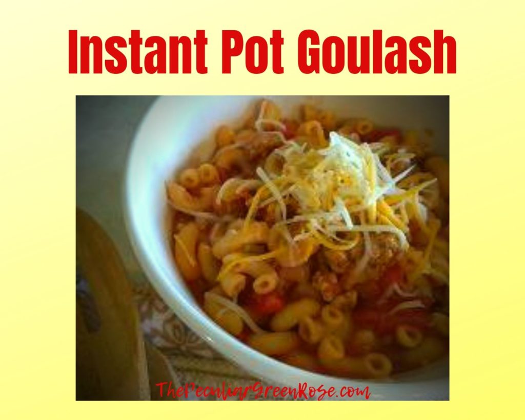 A white bowl filled with instant pot goulash topped with shredded cheese.