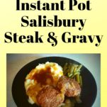 A black plate filled with mashed potatoes, salisbury steak, gravy, onions, and green beans.
