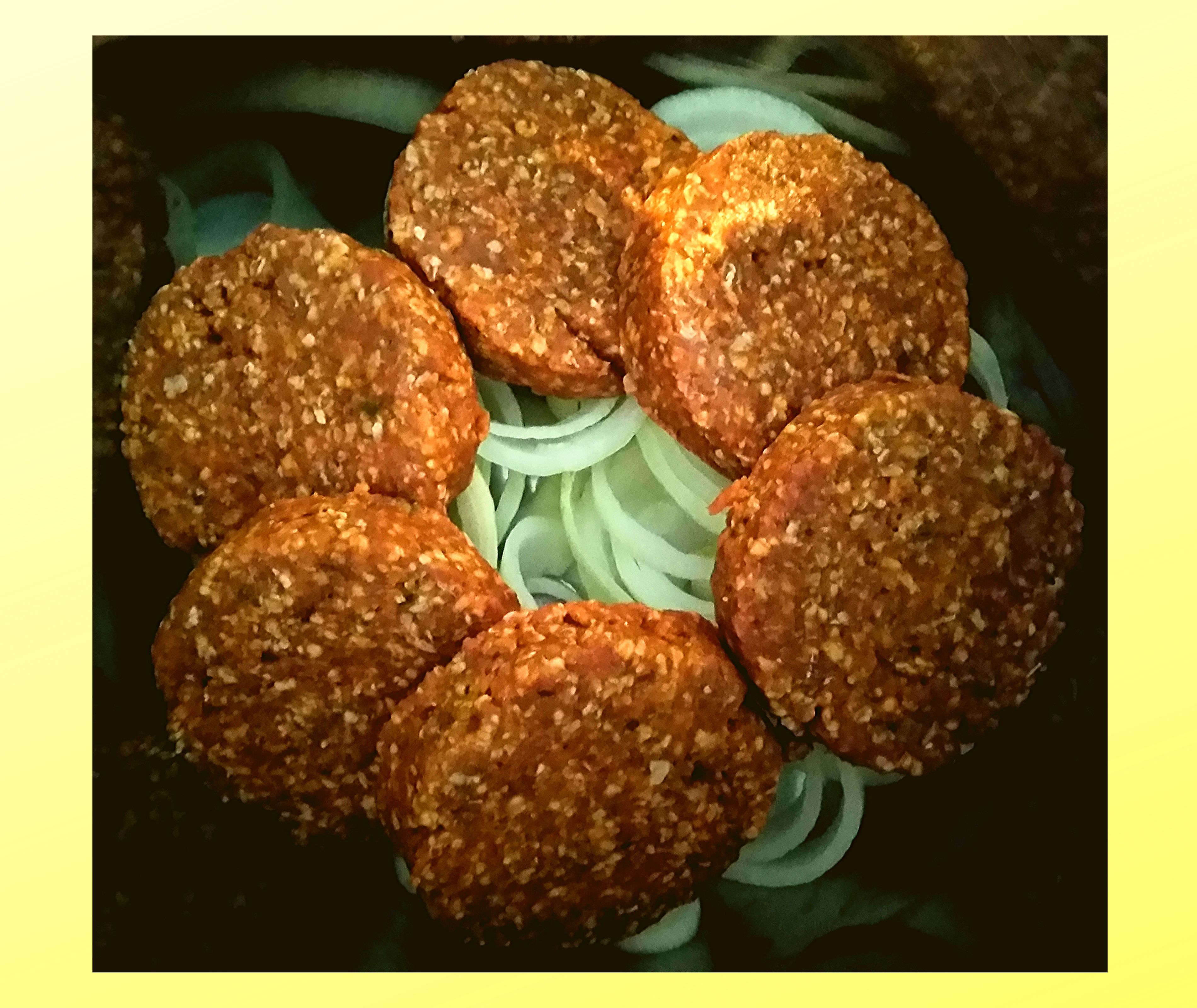 The inside of an Instant Pot filled with sliced onions topped with raw hamburger patties.