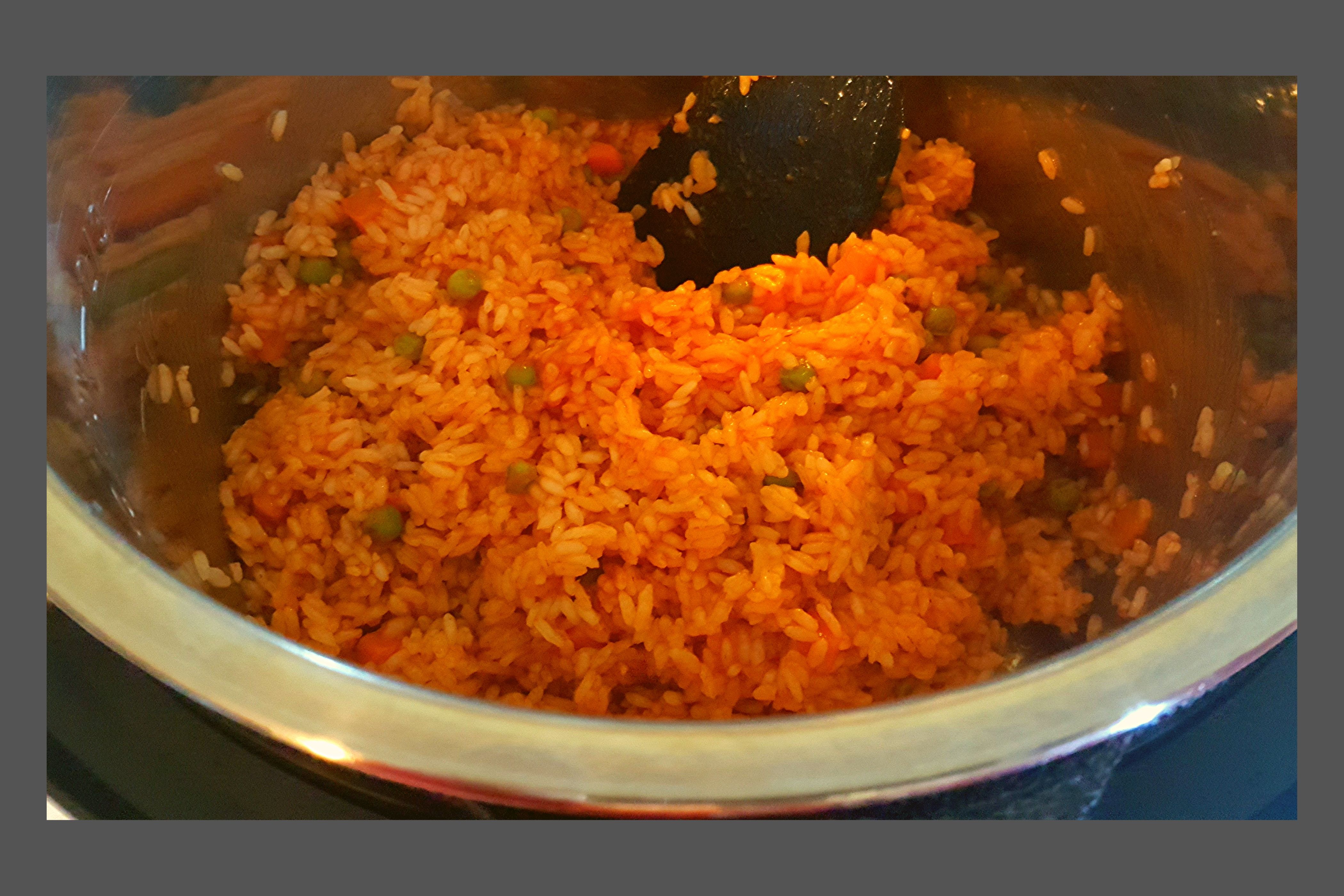 An Instant Pot filled with cooked mexican \ spanish rice with peas and carrotts.