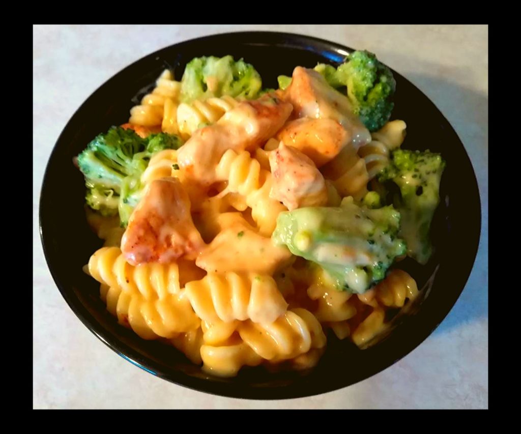 A black bowl filled with instant pot broccoli chicken pasta.