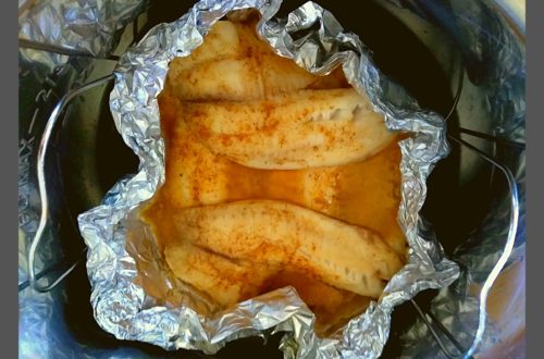 Cooked tilapia fillets inside a foil boat resting in an instant pot.