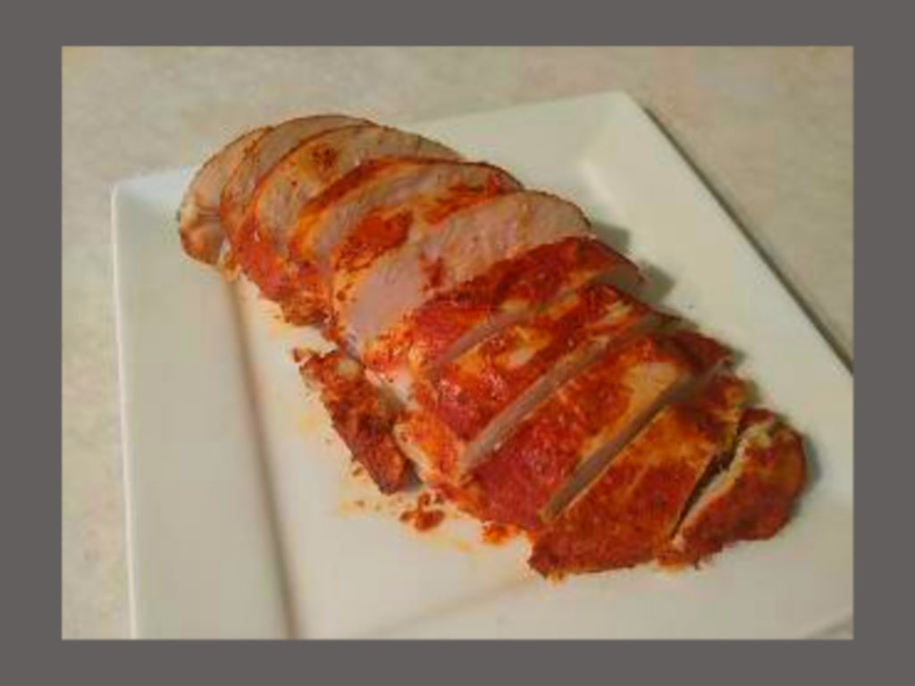 A white square plate with cooked chicken breast sliced.