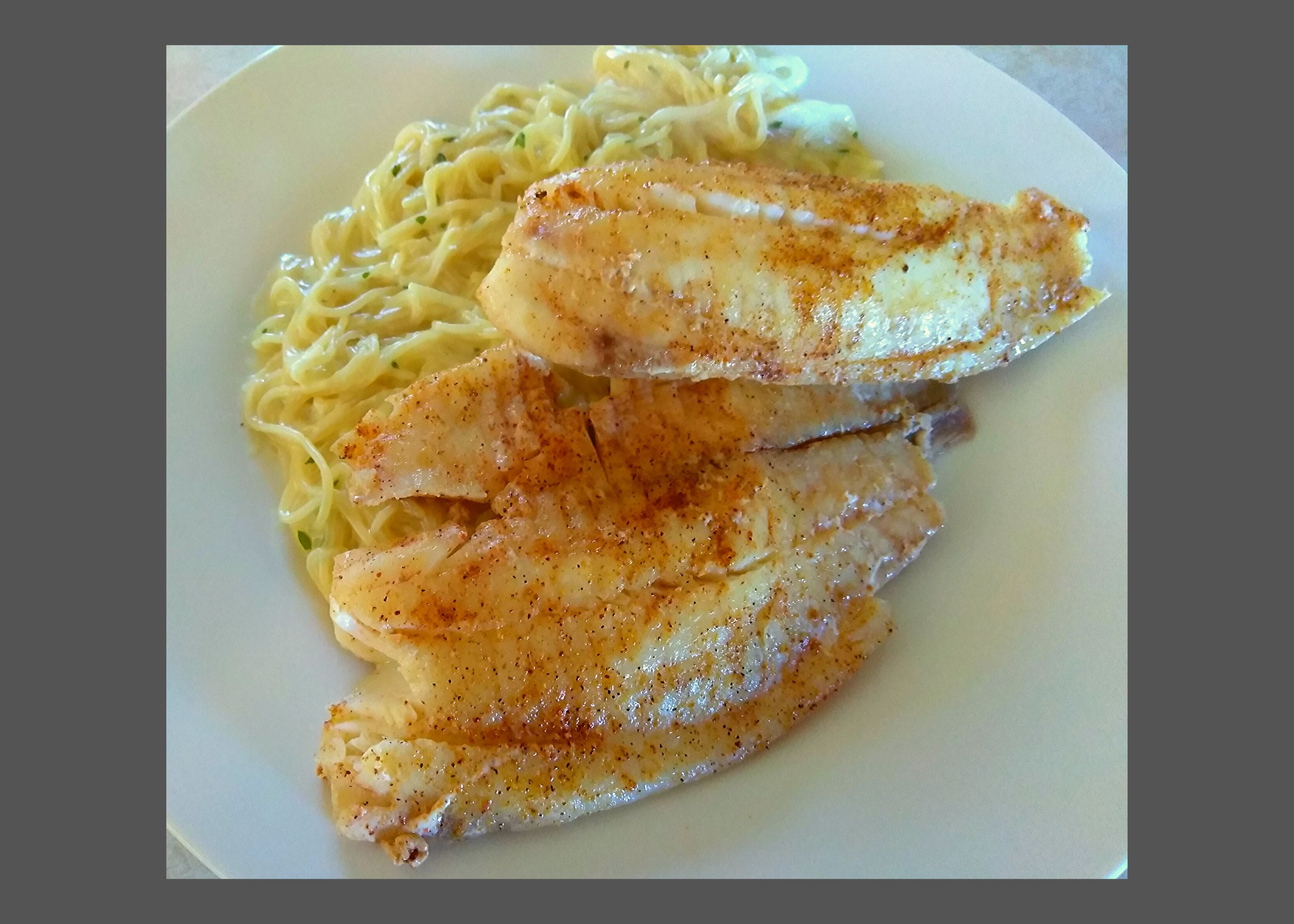 A white plate filled with Instant Pot Tilapia over angel hair noodles.