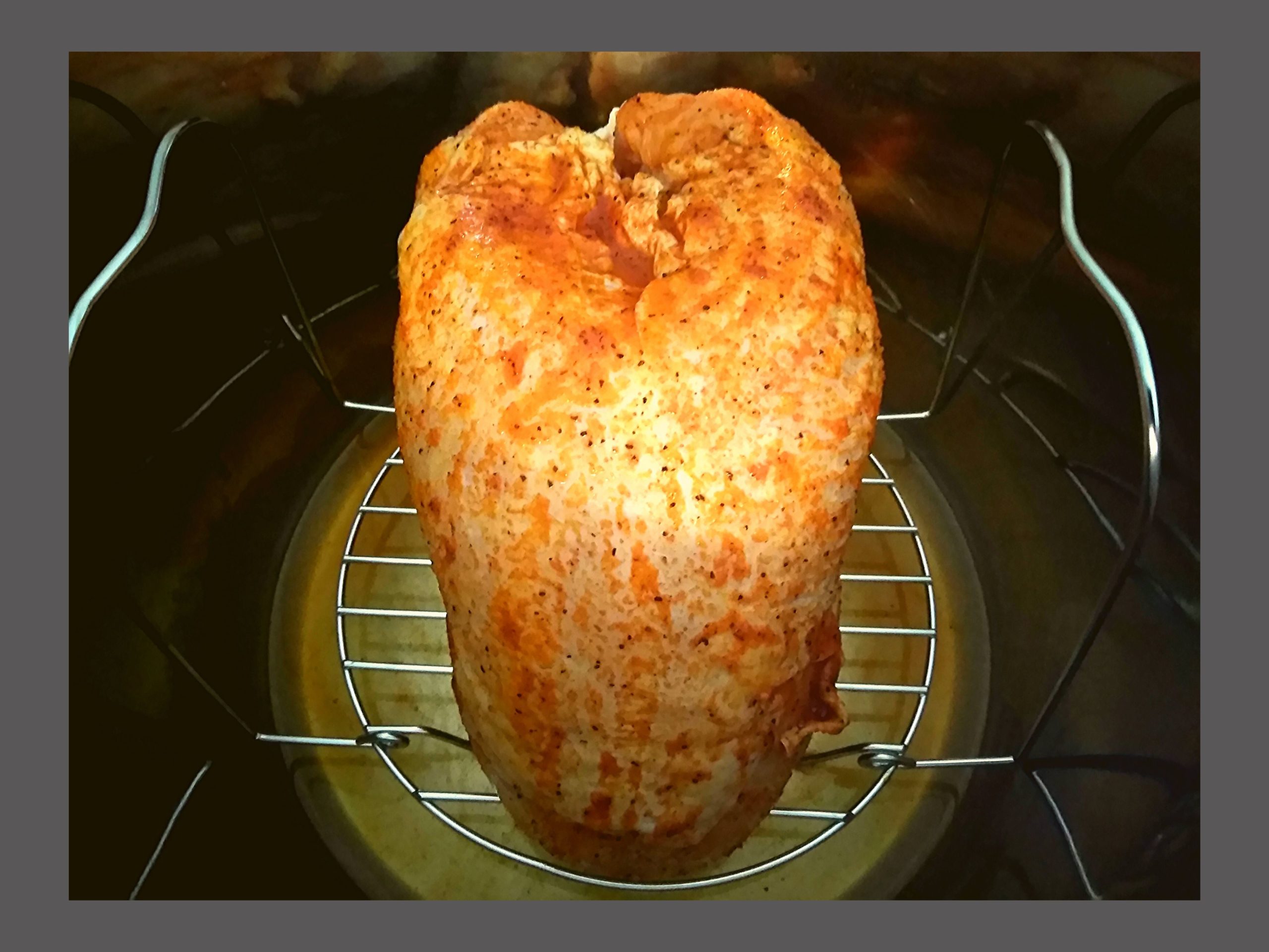 Raw Turkey breast covered in seasoning sitting on a trivet in an Instant pot.