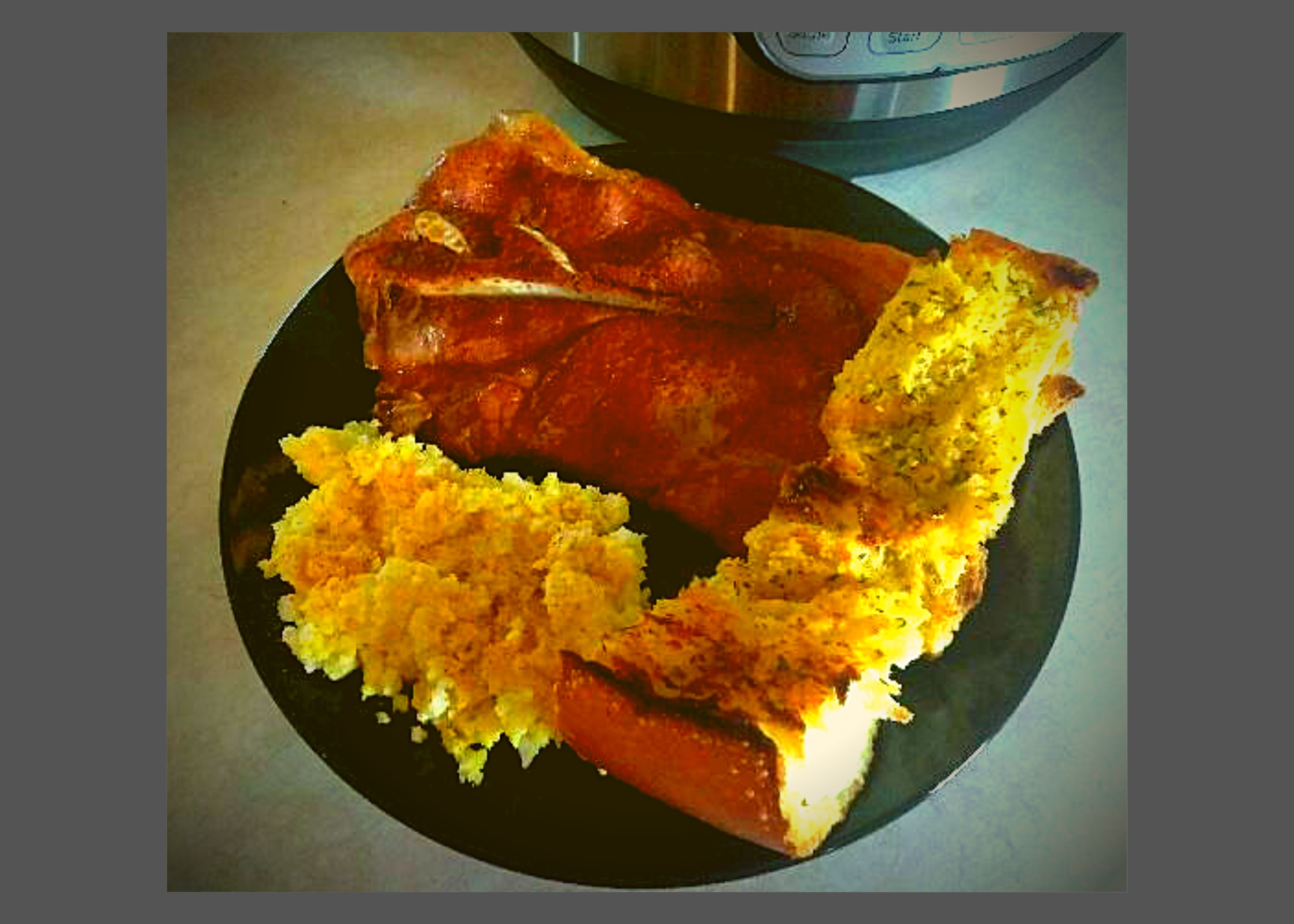 A black plate with Instant Pot BBQ Pork Steak, potato salad, and garlic bread sitting in front of an Instant Pot