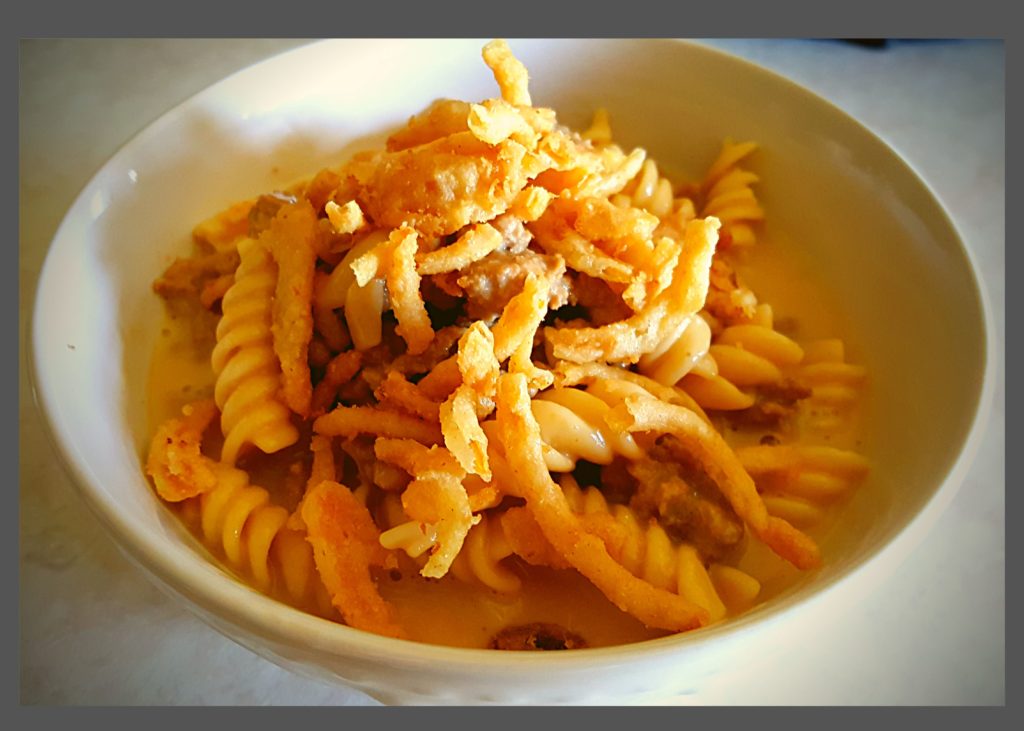 A white bowl filled with Instant pot hamburger helper topped with fried onions.