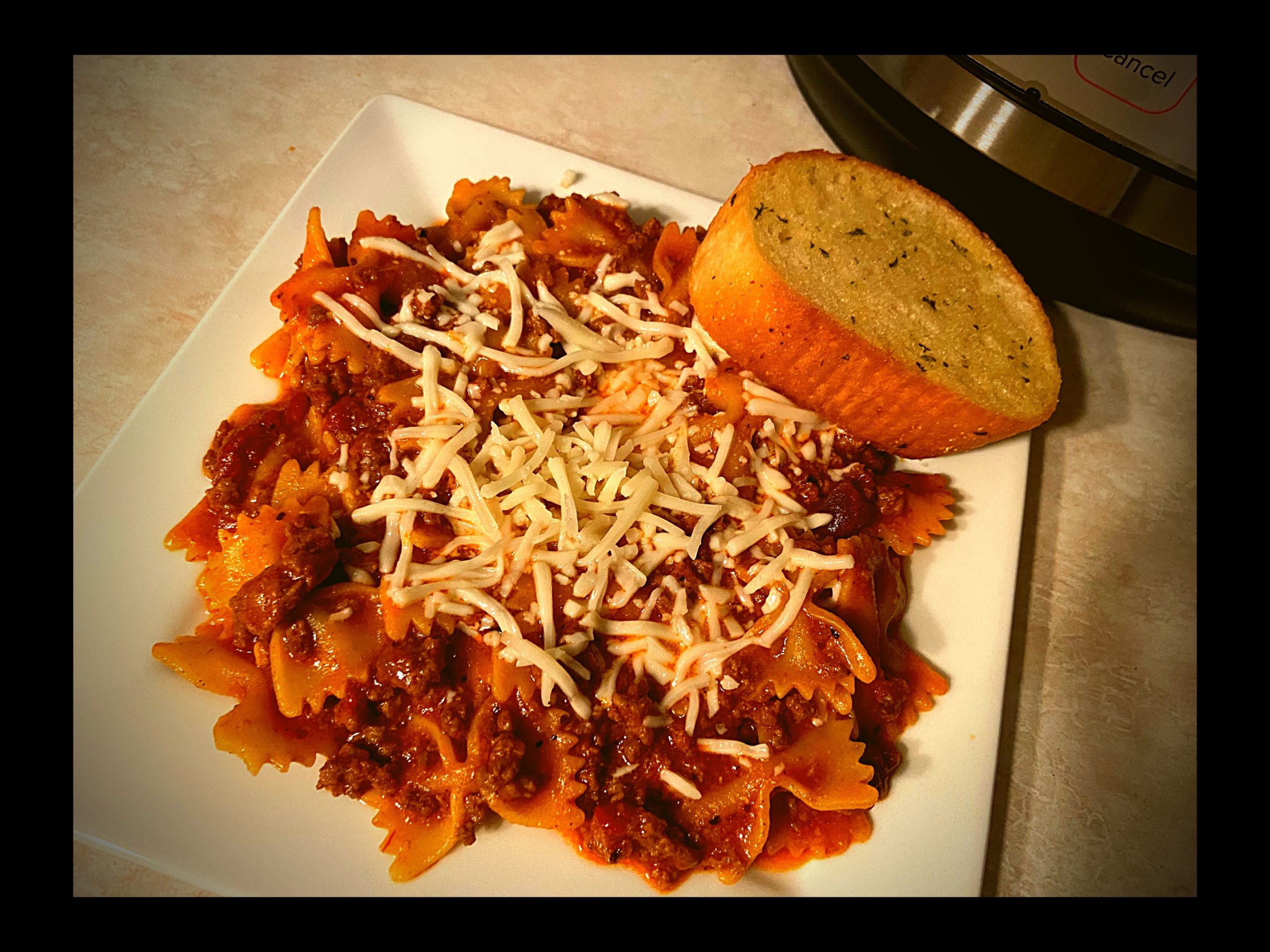 A white plate filled with Instant Pot Lasagna bow tie pasta and a garlic bread.