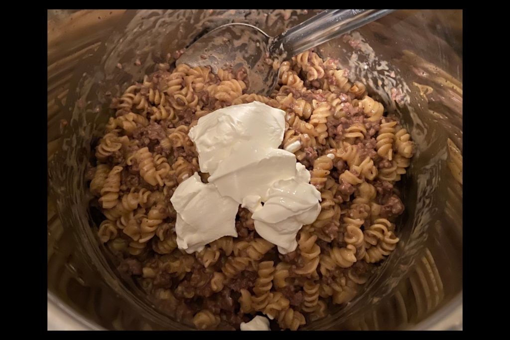 Instant Pot filled with ground beef stroganoff topped with sour cream