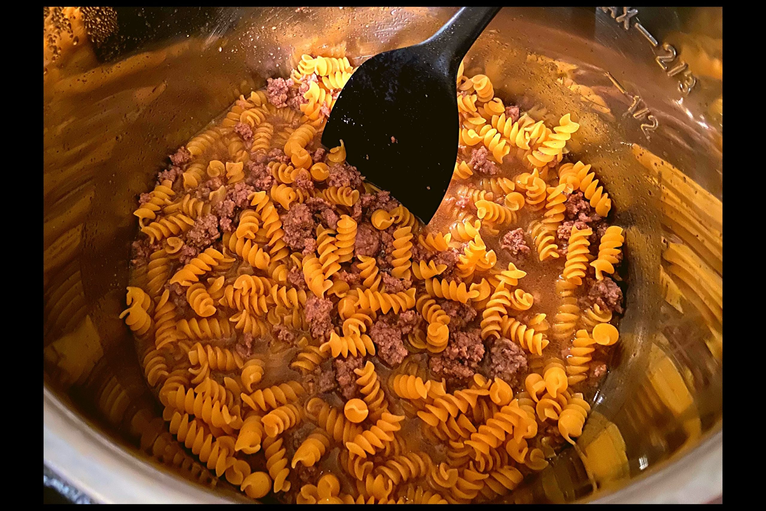 Instant Pot filled with ground meat, beef broth, and rotini noodles