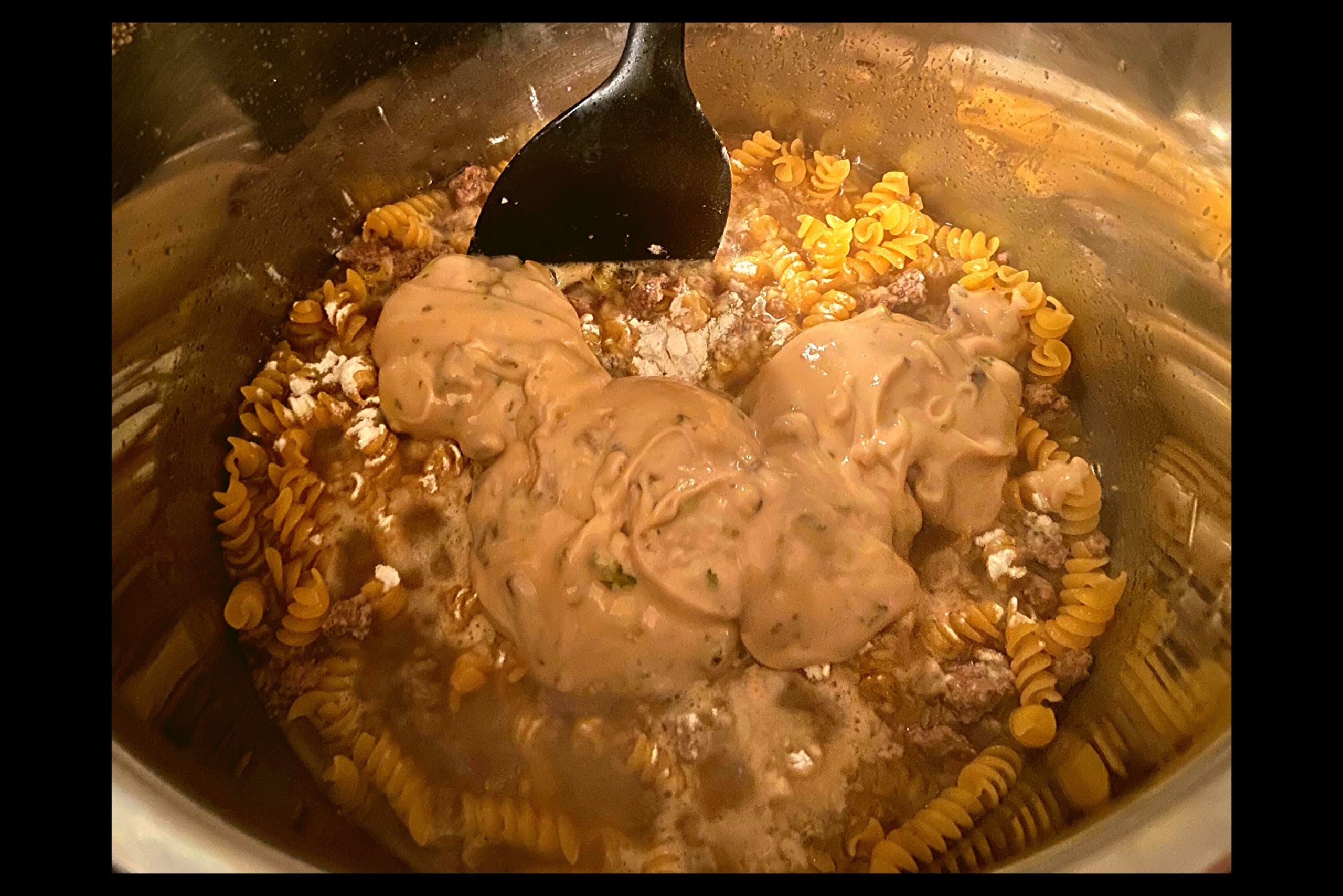 Instant Pot filled with ground meat, beef broth, rotini noodles, flour, and cream of mushroom and roasted garlic