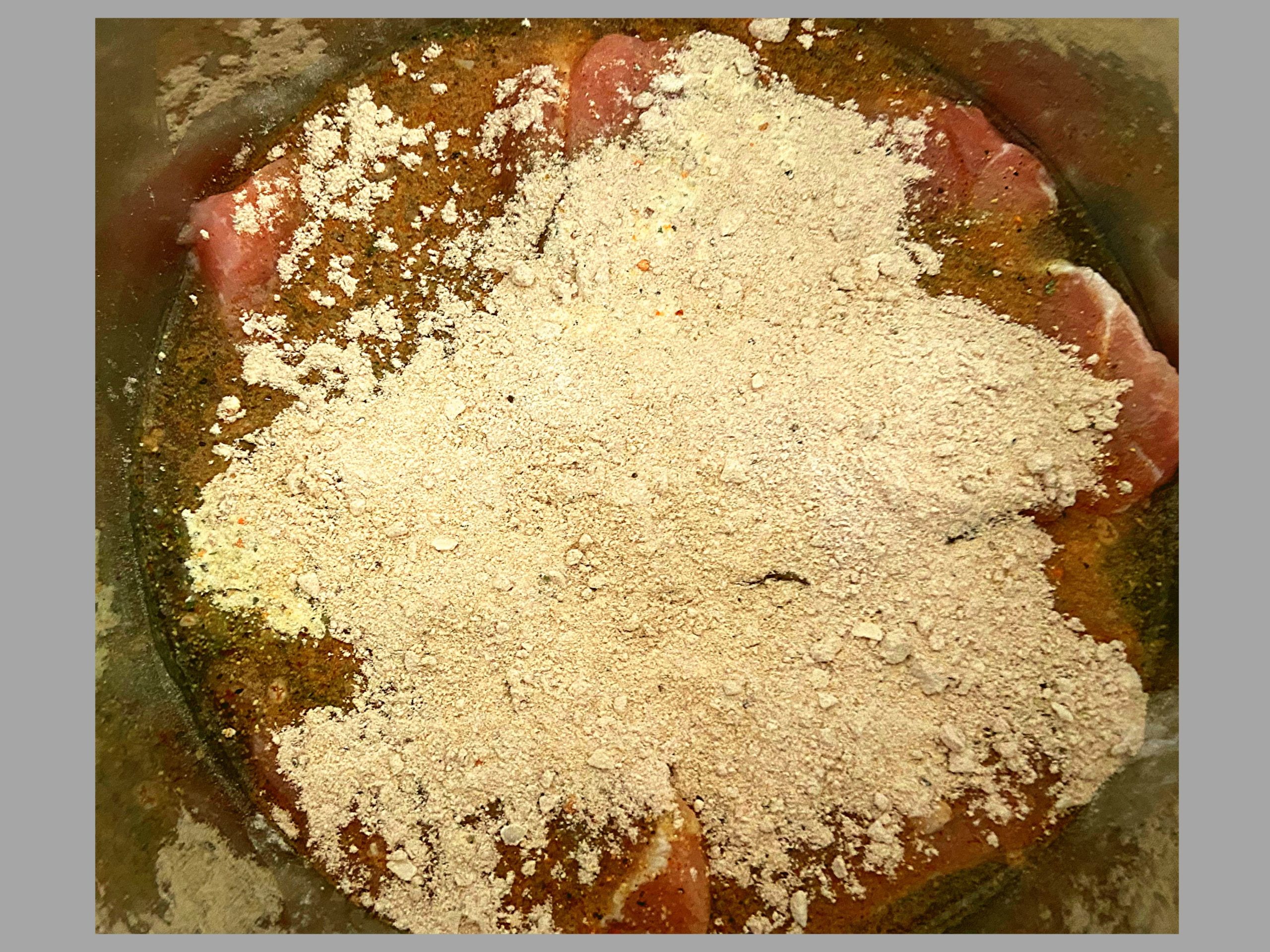 The inside of an Instant Pot with raw pork roast topped with dry ranch dressing, dry italian dressing, and dry pork gravy mix.