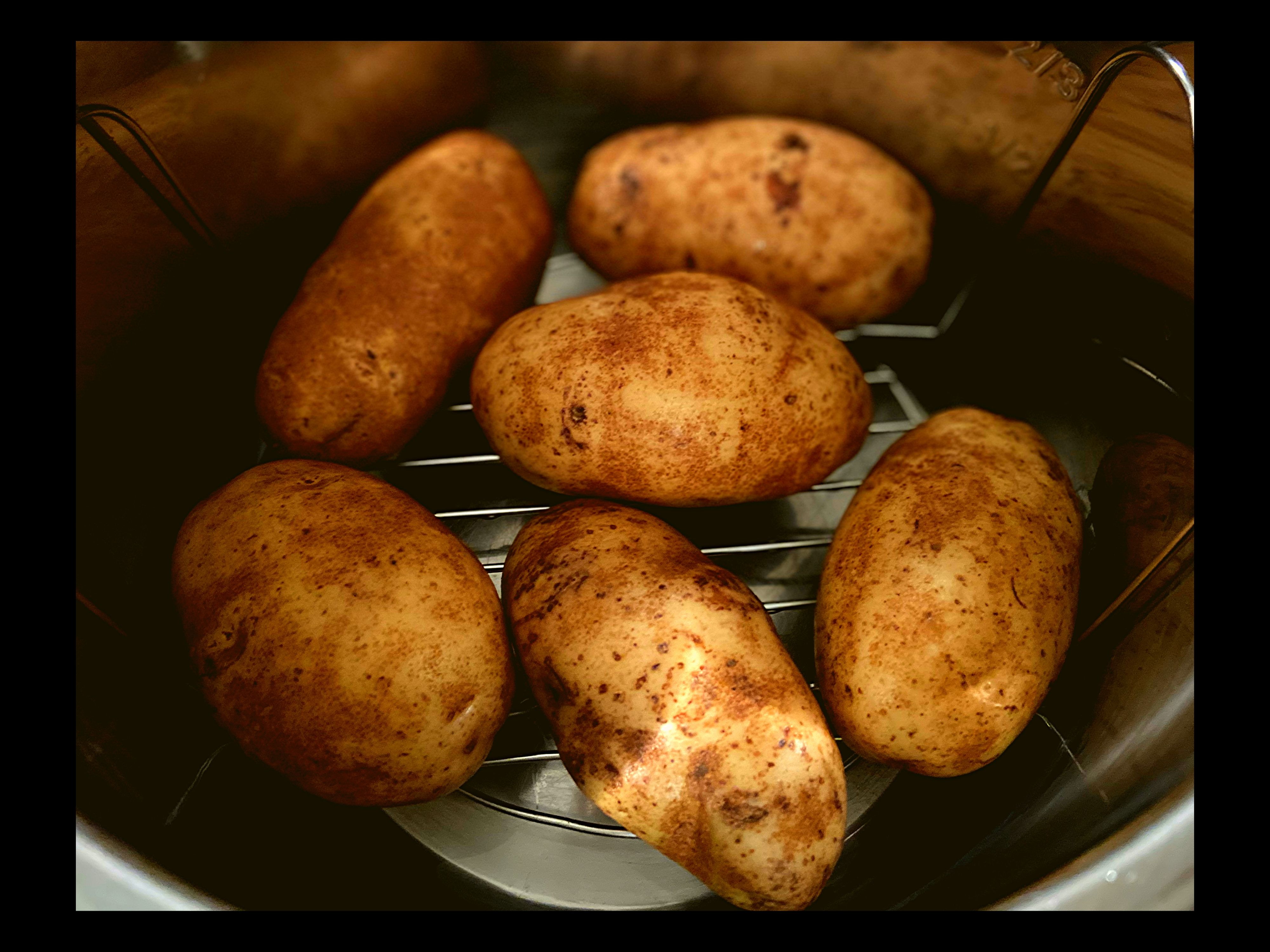 6 raw potatoes inside of an Instant Pot on a trivet.