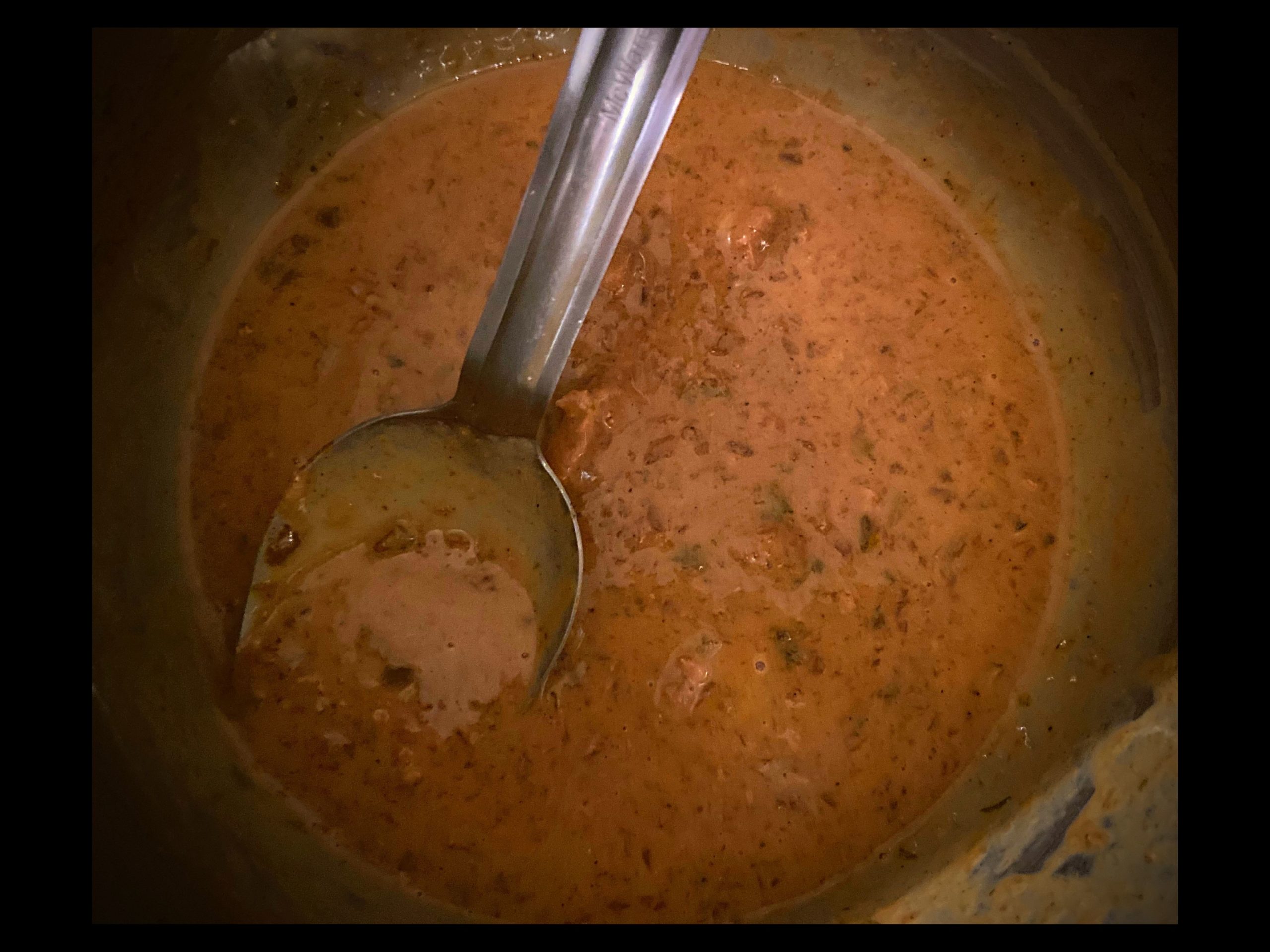 Brown gravy inside an Instant Pot with a scoop of sour cream