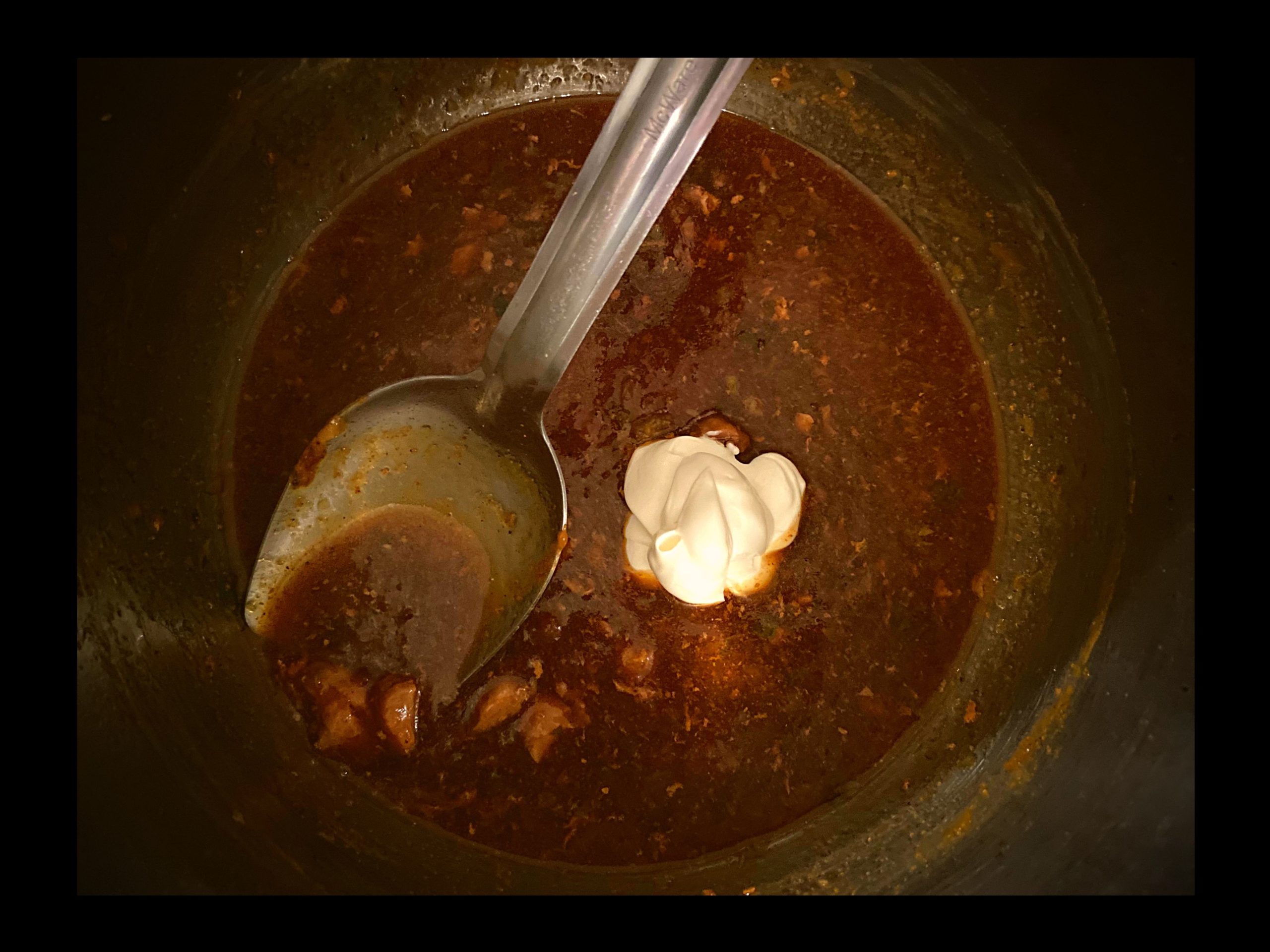 Brown gravy inside an Instant Pot with a scoop of sour cream
