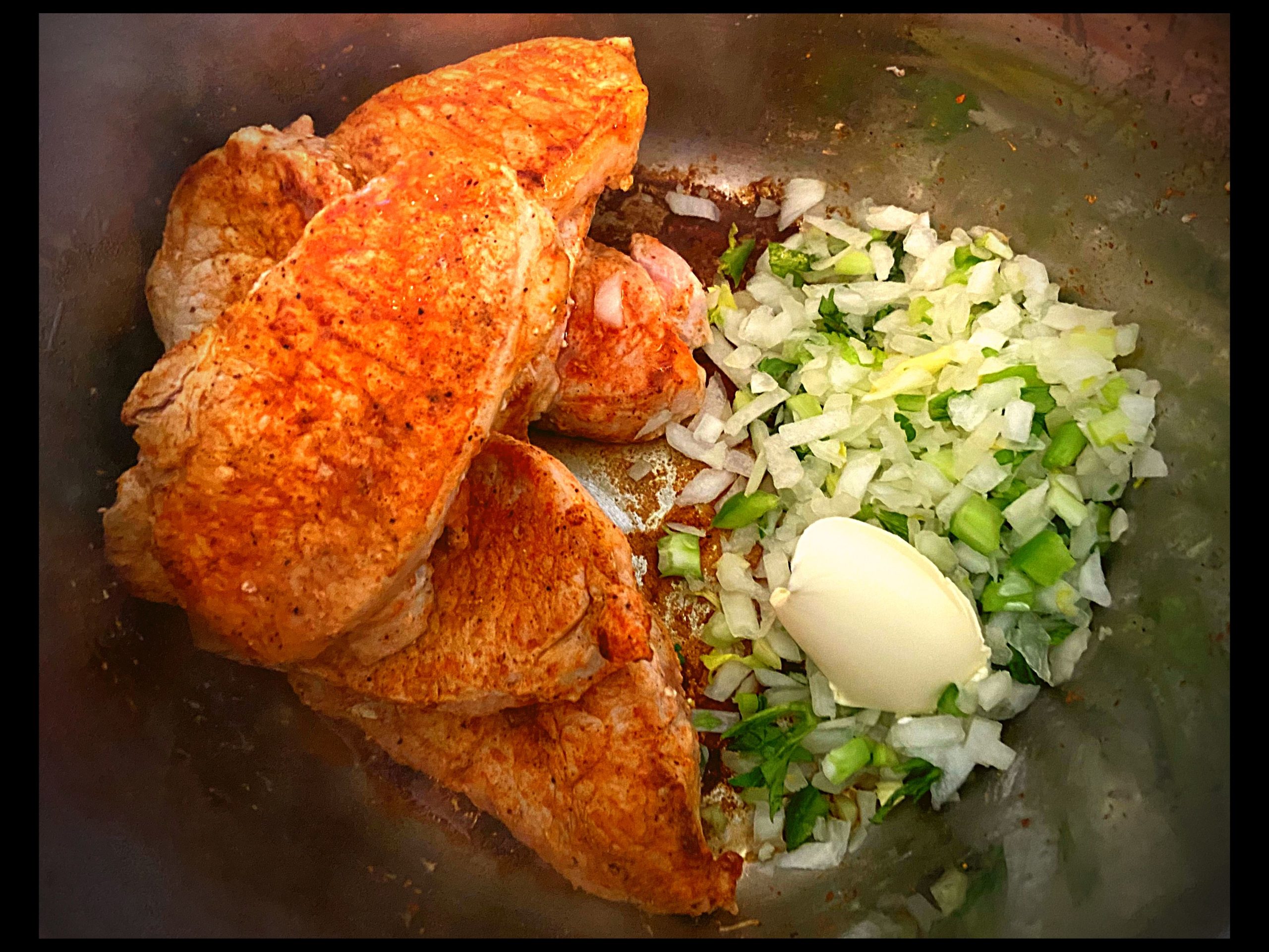 Browned Pork Chops piled up on one side with butter, onions, celery, and bell peppers on the other side