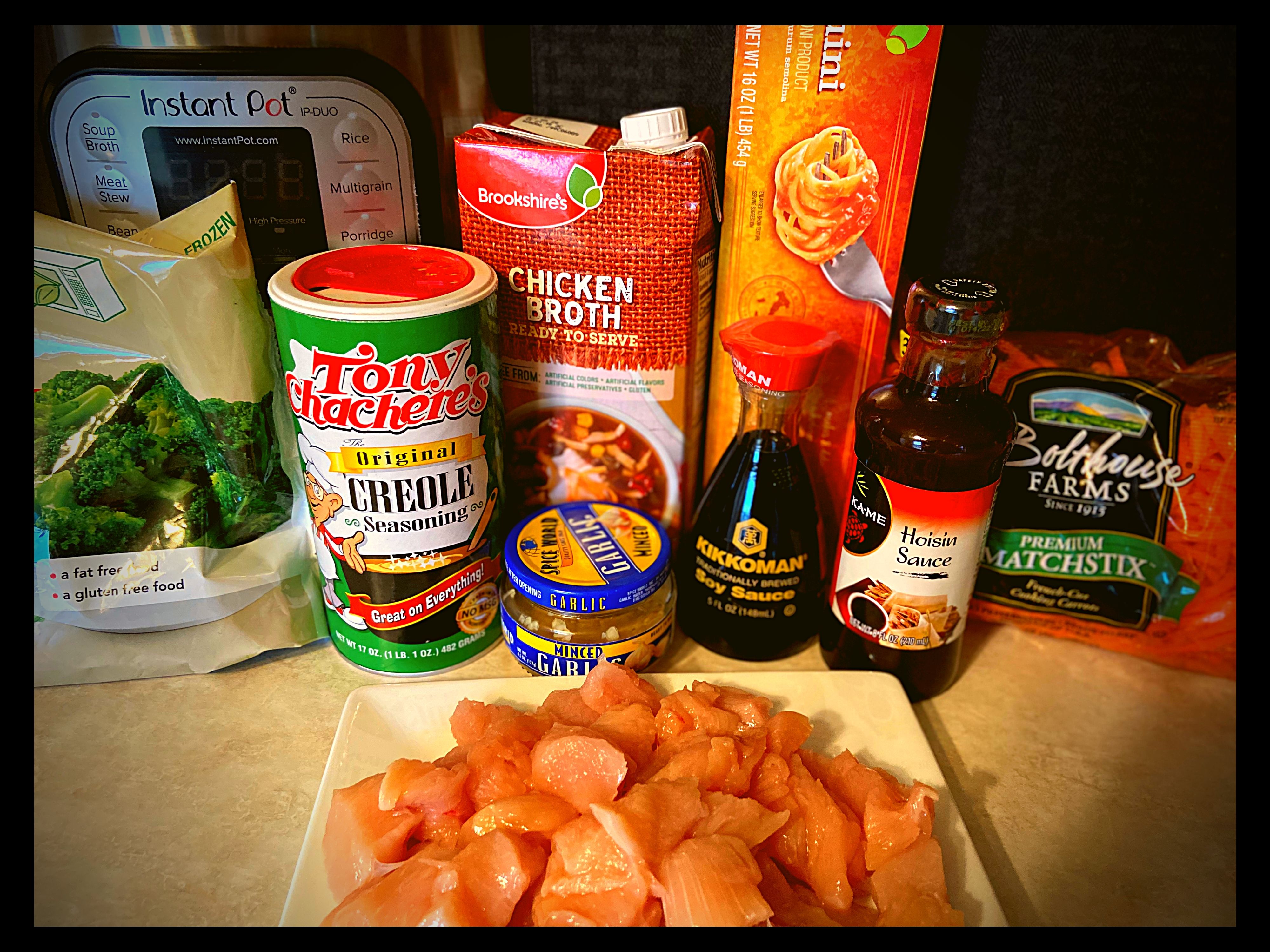 All the ingredients to make Instant Pot Chicken Lo Mein sitting on a counter top in front of an Instant Pot.