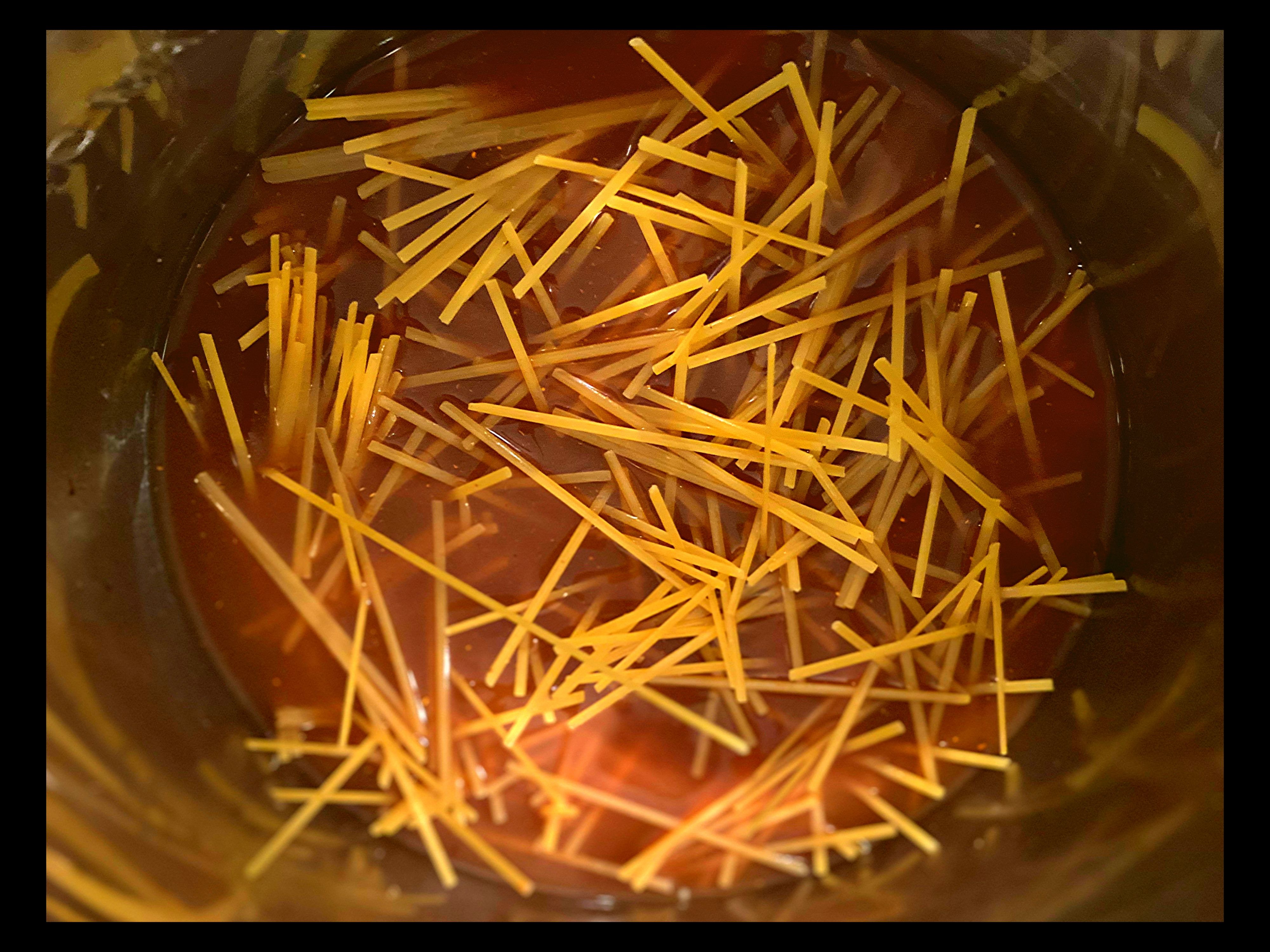 The inside of an Instant Pot with Hoisin and soy sauce mixed with dry linguine noodles.