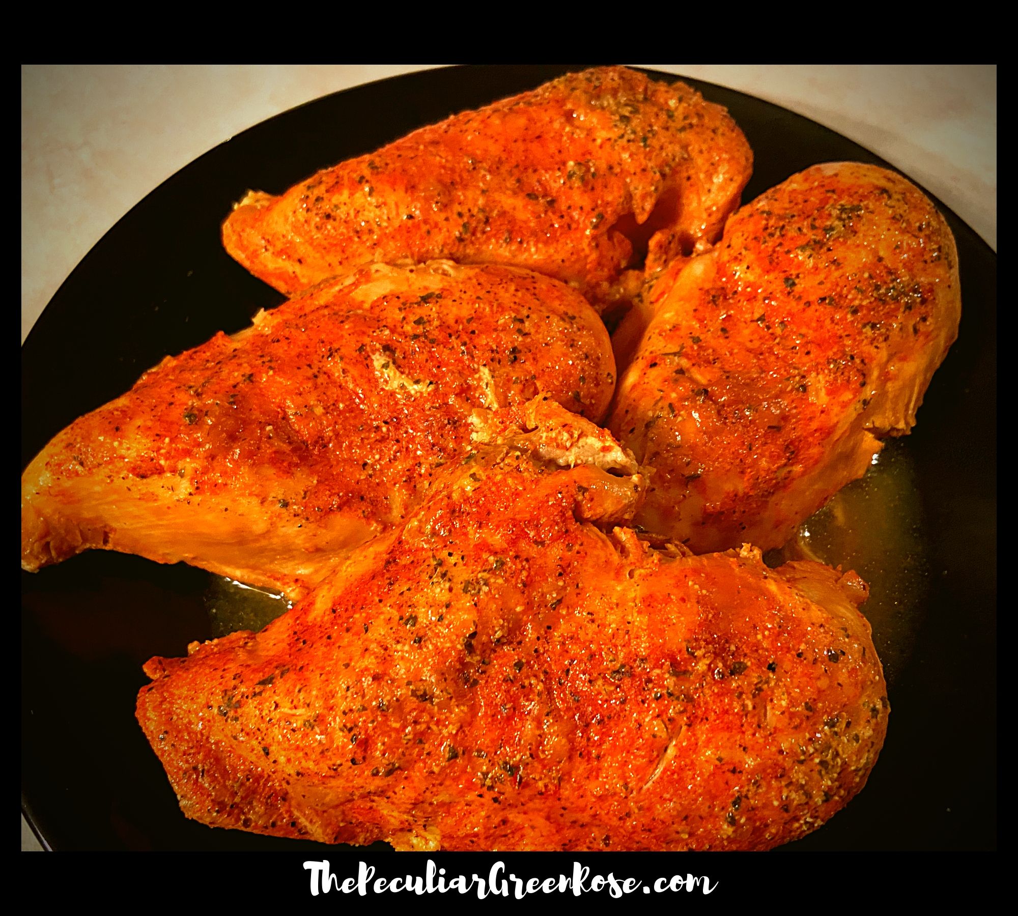 A black plate filled with 4 large chicken breasts covered in 3 packets of seasoning.