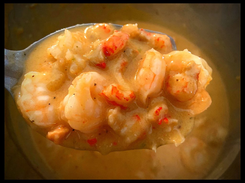 A large spoon full of shrimp and crawfish etouffe over and Instant pot filled with etouffee.