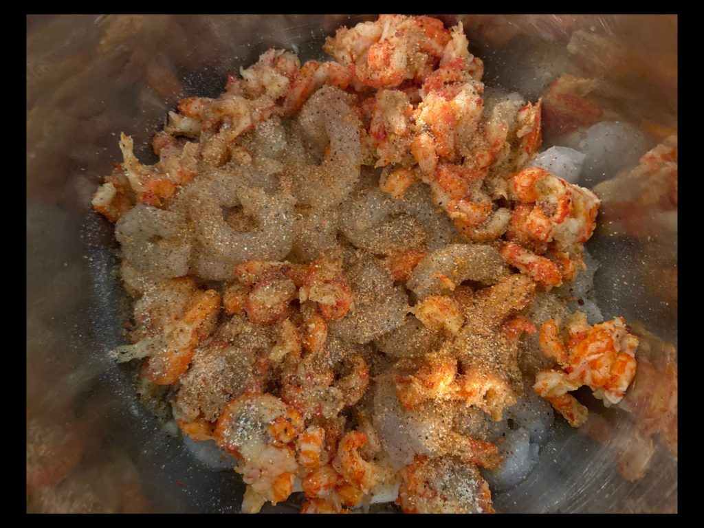 An instant pot filled with raw shrimp and crawfish tails covered in italian dressing seasoning (powder) and tony chachere's seasoning