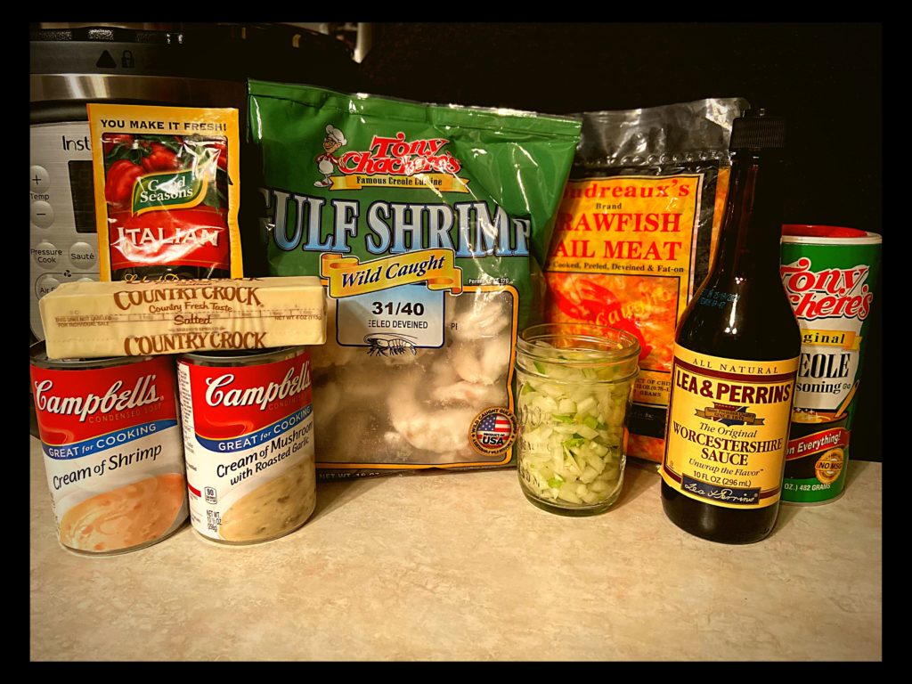 An instant pot, italian dressing seasoning (powder) packet, stick of butter, can of cream of shrimp, can of cream of mushroom with roasted garlic, bag of shrimp, bag of crawfish tails, 1 cup of diced onion, bell pepper, and celery and a bottle of worcestershire sauce sitting on a kitchen counter.