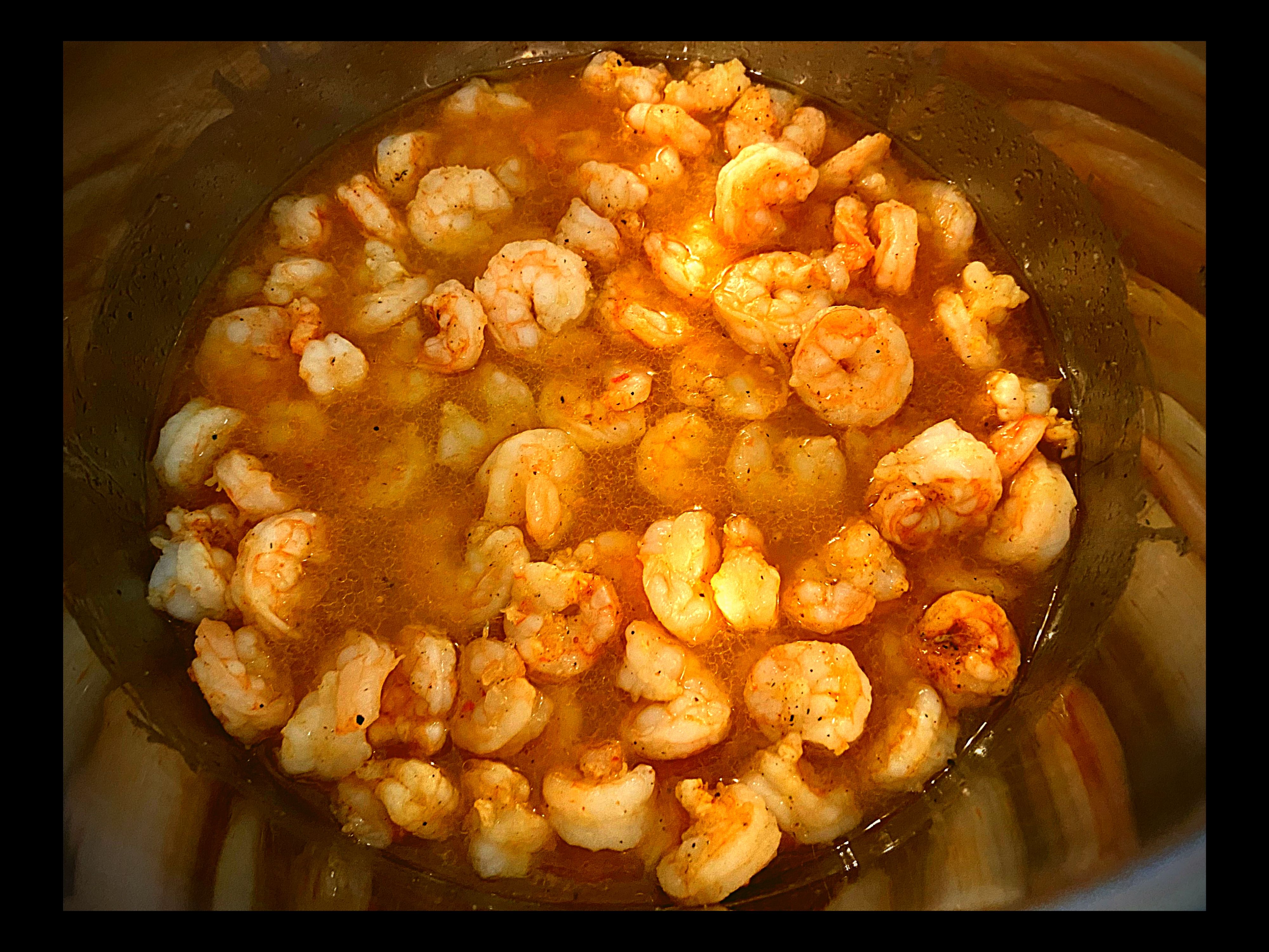 The inside of an Instant filled with cooked shrimp in butter, italian seasoning, and tony chacheres.