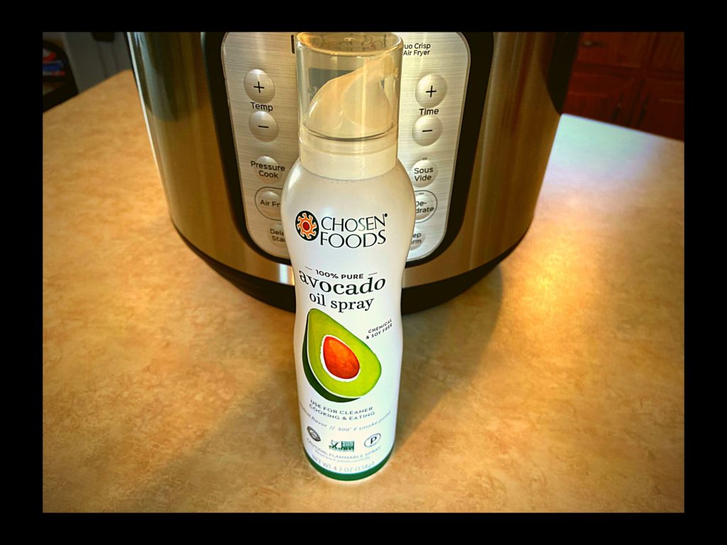 A bottle of Avocado Spray sitting in front of a Instant pot Duo Crisp plus air fryer on a kitchen counter.