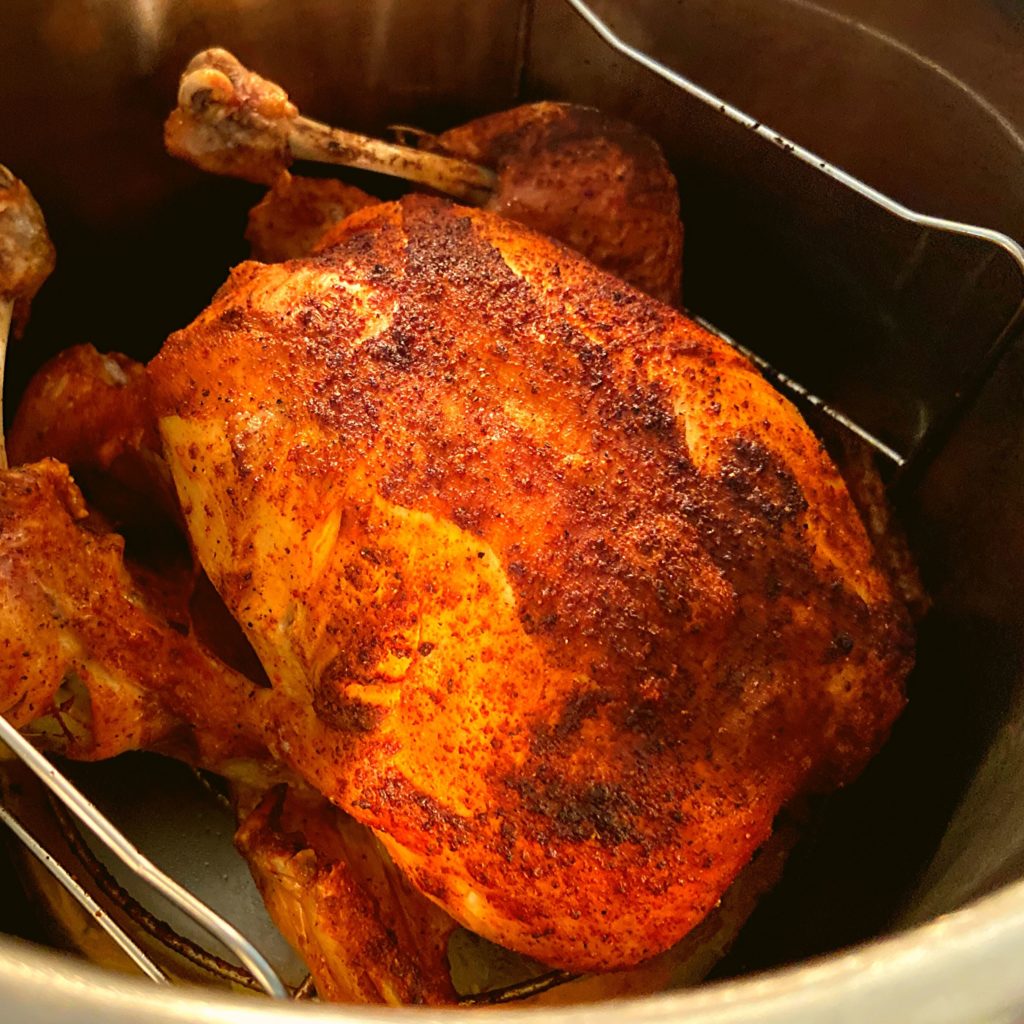 A crispy browned whole chicken inside of an Instant Pot Duo Crisp plus air fryer.