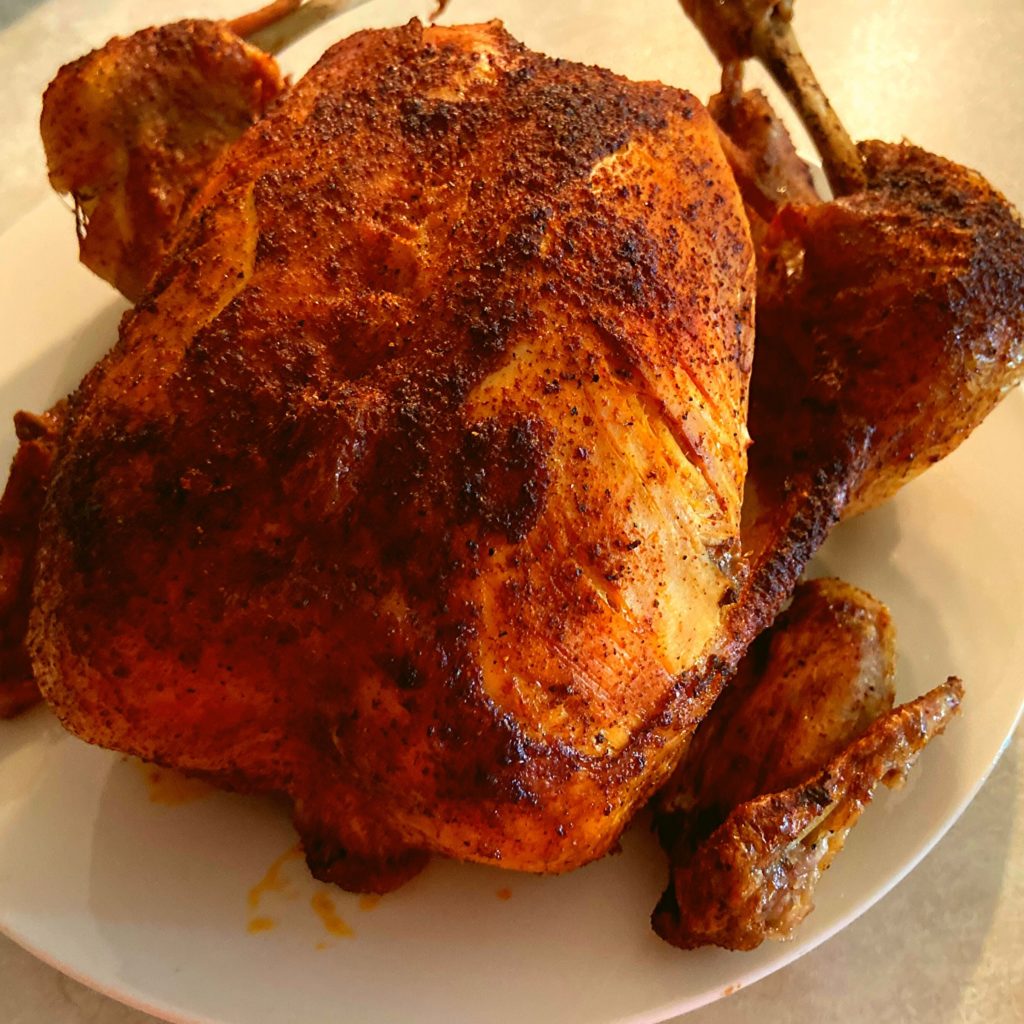 A crispy browned whole chicken sitting on a kitchen counter.