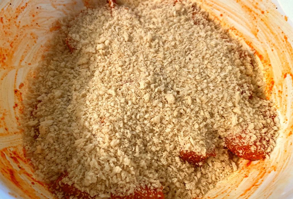 A white bowl filled with boneless chicken bites covered in panko bread crumbs.