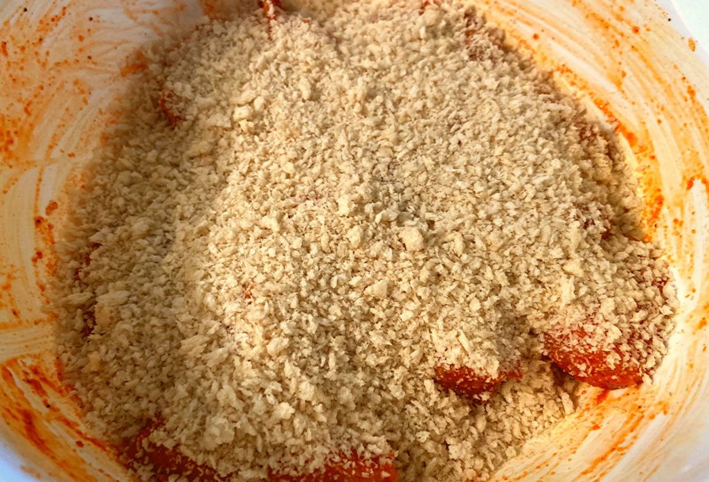 A white bowl filled with boneless chicken bites covered in panko bread crumbs.