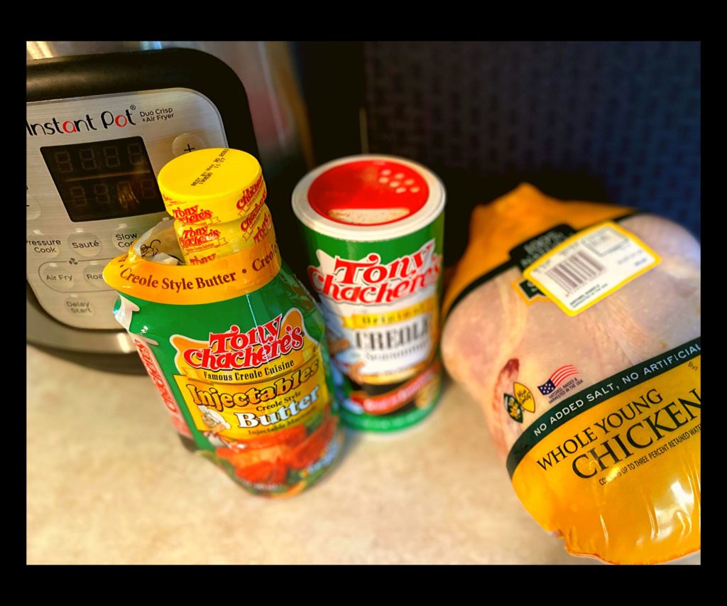 an instant pot duo crisp, tony chachere's seasoning, tony chachere's injectable marinade, and a whole raw chicken sitting on a kitchen counter.