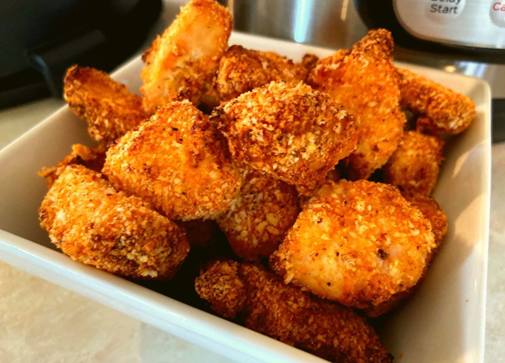 Instant Pot Duo Crisp Boneless Chicken Bites in a white square bowl on a kitchen counter in front of and Instant Pot Duo Crisp plus air fryer.