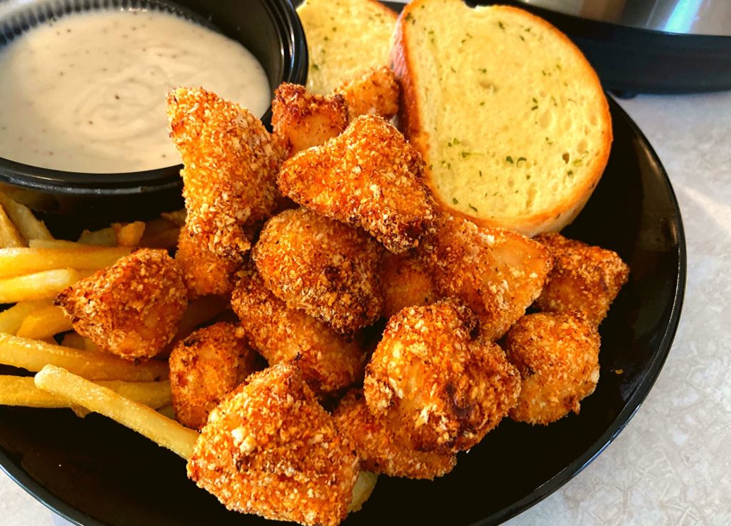 Instant Pot Duo Crisp Boneless Chicken Bites on a black plate with french fries, garlic toast, and white gravy.