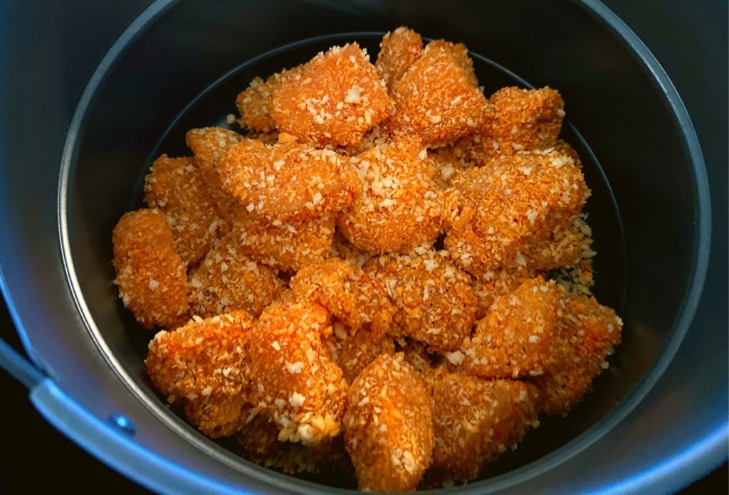 Raw boneless chicken bites covered in Panko breadcrumbs sitting in a Instant Pot Duo Crisp air fryer basket.