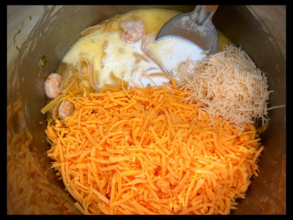The inside of an Instant Pot filled with Shredded velveeta cheese and shredded parmesan cheese.