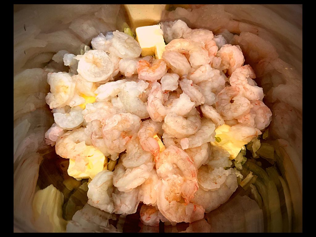 The inside of an Instant Pot filled with raw shrimp