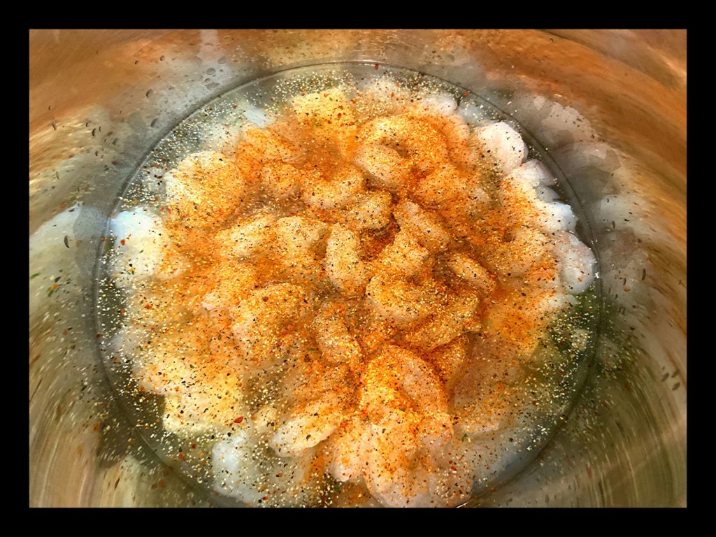 The inside of an Instant Pot filled with raw shrimp, water, tony chachere's seasoning and Italian dressing mix (powder)