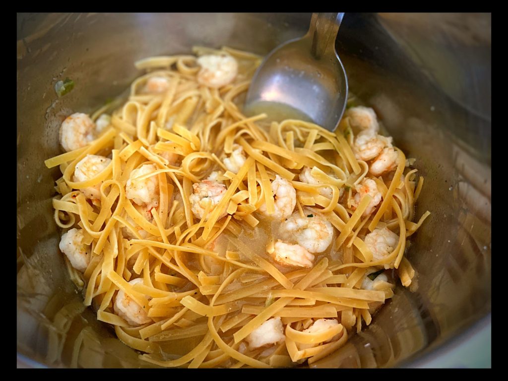 The inside of an Instant Pot with Shrimp and Fettuccine noodles.