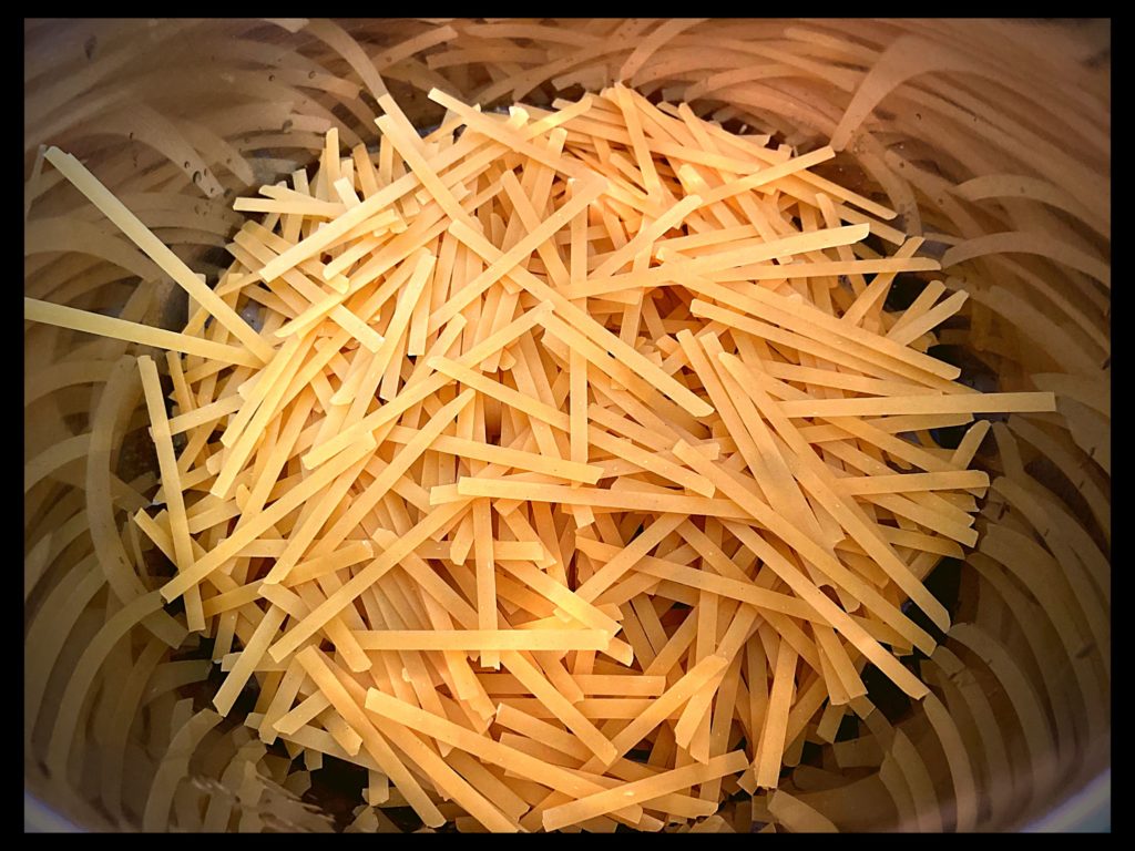 The inside of and Instant Pot filled with uncooked fettuccine noodles.