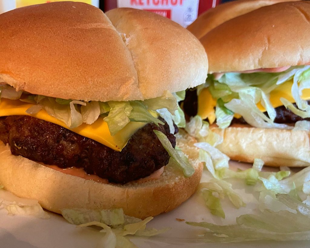 2 Instant Pot Duo Crisp hamburgers sitting on a white plate.