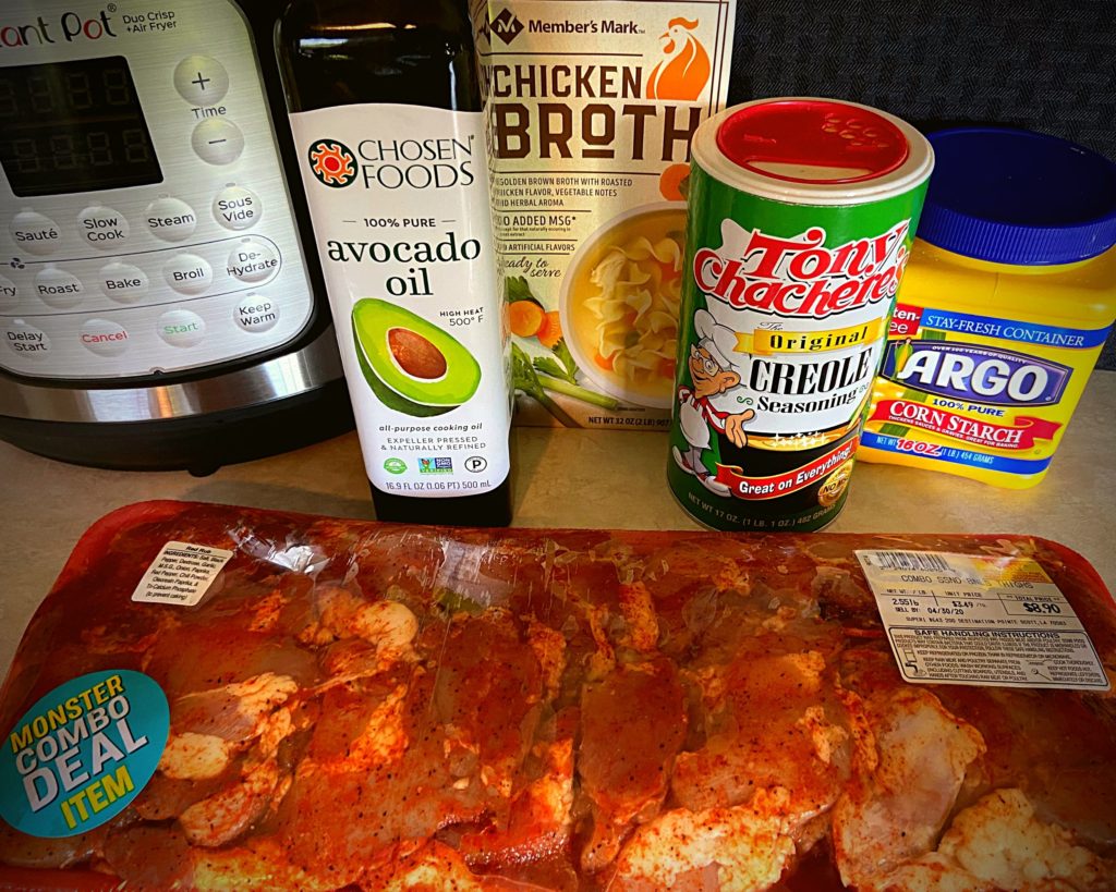 An Instant Pot, package of raw marinated chicken thighs, avocado oil, chicken broth, tony chacheres seasoning, and corn starch.