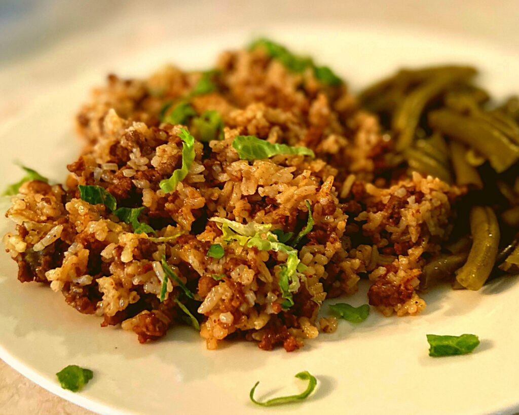 Instant Pot Ground beef and rice next to green beans on a white plate.