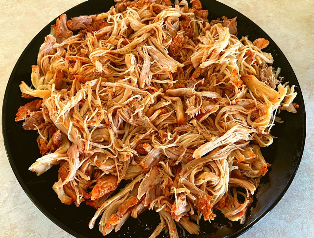 A black plate topped with shredded chicken.