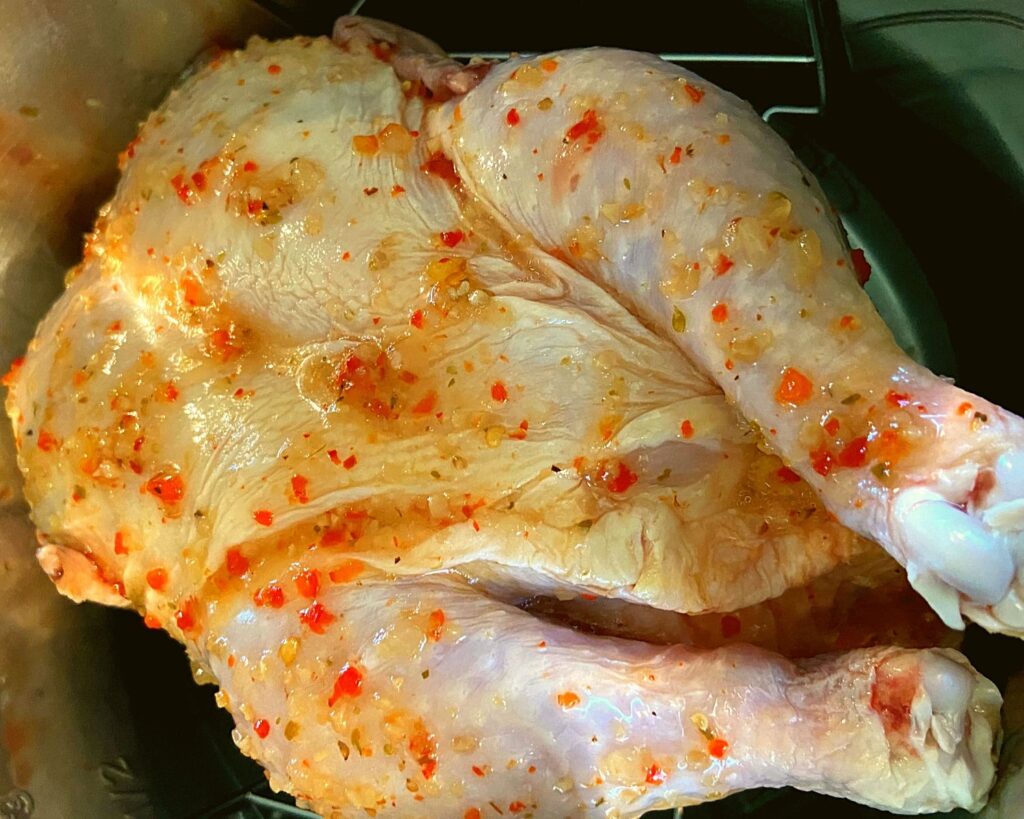 A raw chicken covered in Italian Dressing sitting in an Instant Pot.