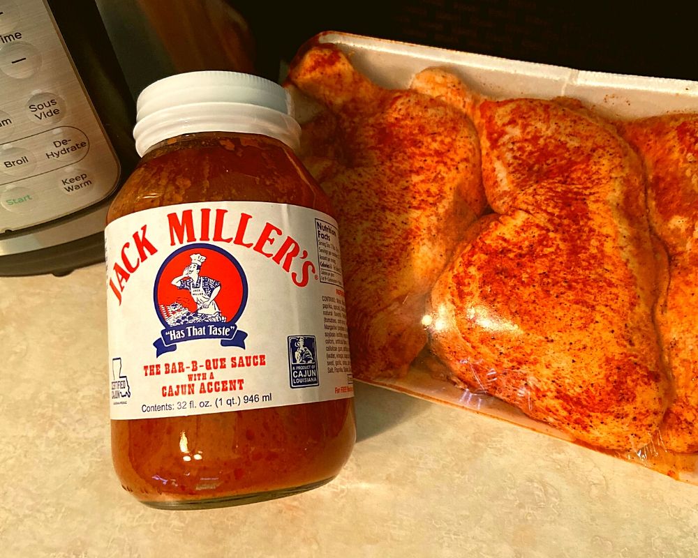 An Instant Pot, bottle of Jack Miller BBQ Sauce, and marinated Chicken Leg Quarters