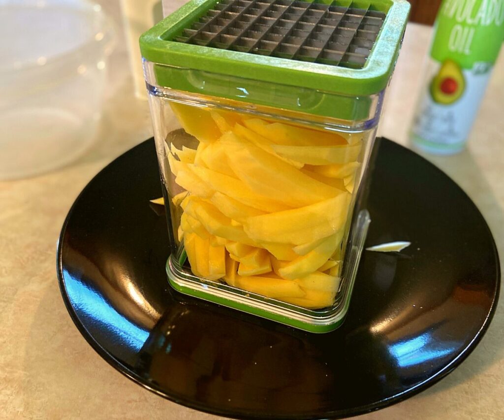 A french fry cutter full of chopped potatoes.